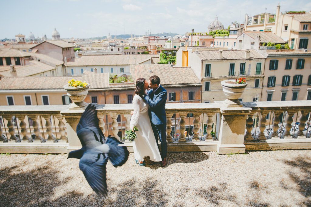 Blue heels, blue suit, and blue-colored bird in urban Italy by elopement photographer Peggy Picot