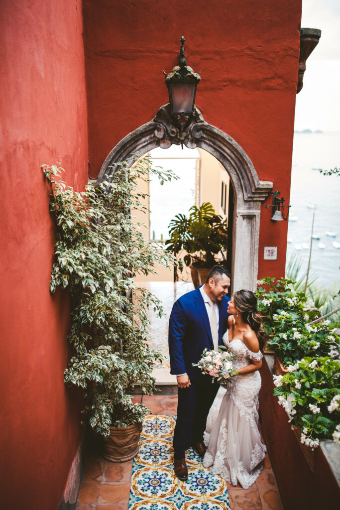 Photo of couple in Amalfi Coast by red wall over the Mediterranean by Peggy Picot
