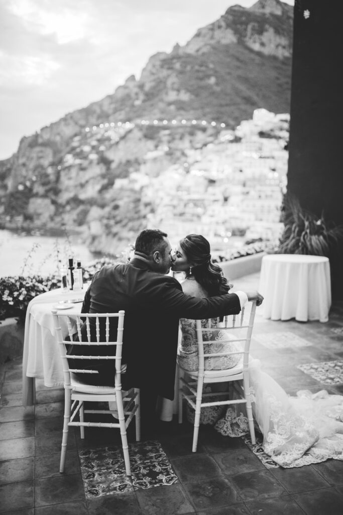 Newlyweds kissing at dinner in Positano restaurant on cliff. Photo by Peggy Picot