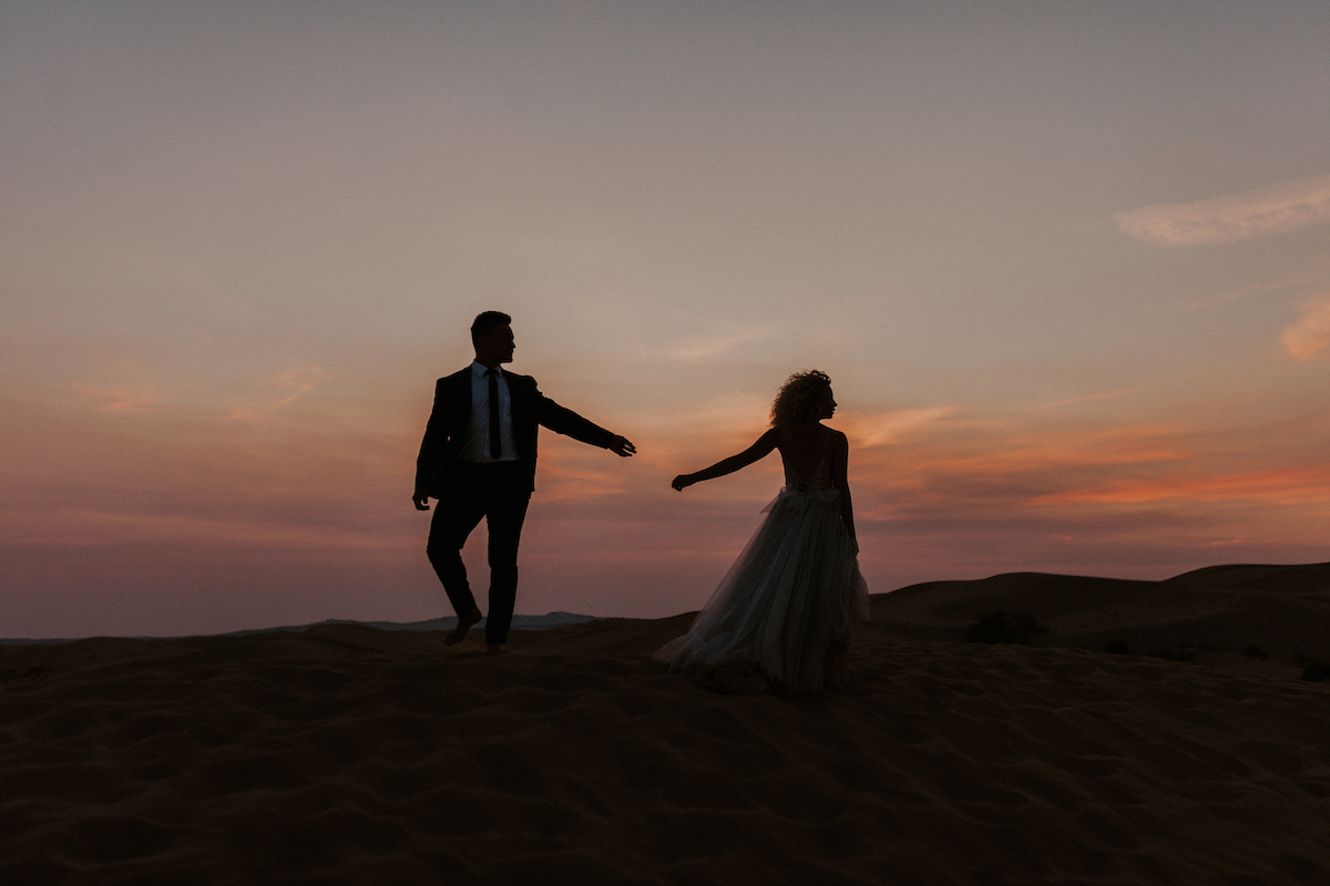Couple Walking Away on the Sand Dunes at Sunset