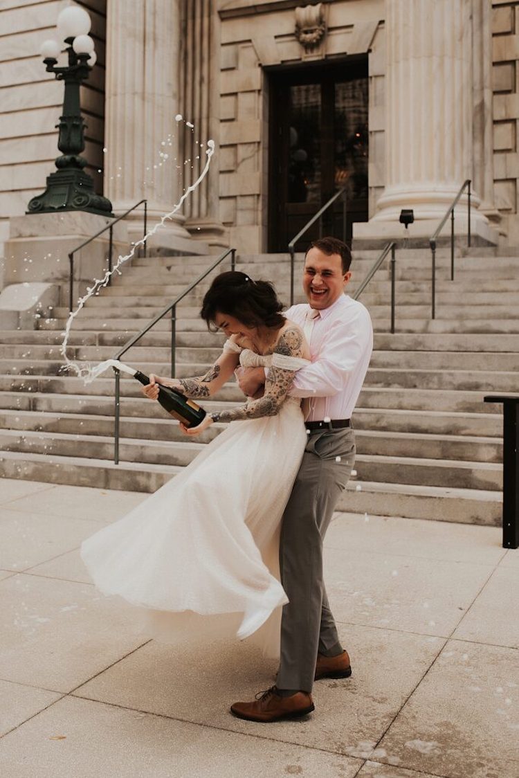 Florida Elopement Photographer Hazography - Art of Eloping. Newlyweds twirling with champagne at foot of City Hall.