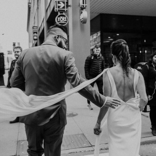 Newlyweds cross street in downtown Chicago with their backs to camera